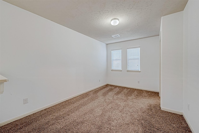 carpeted empty room with baseboards, visible vents, and a textured ceiling