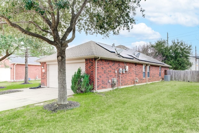 view of side of home with brick siding, solar panels, concrete driveway, a lawn, and an attached garage