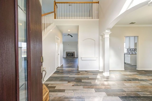 entryway with arched walkways, dark wood finished floors, a fireplace, crown molding, and baseboards