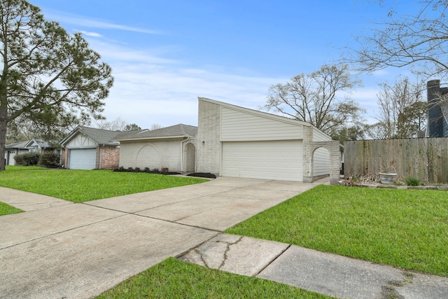 mid-century inspired home with brick siding, concrete driveway, an attached garage, fence, and a front yard