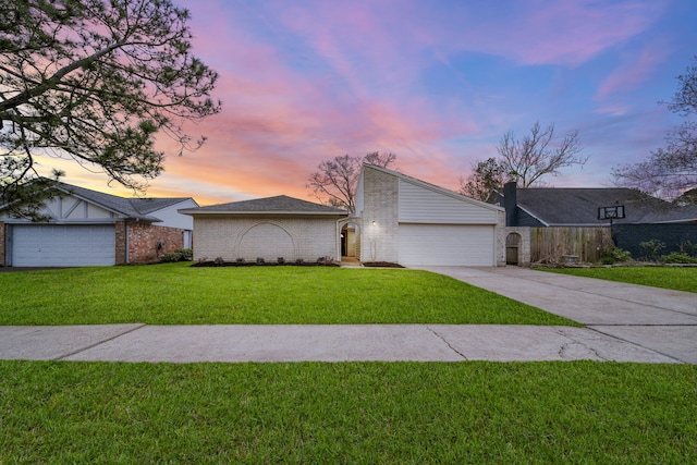 mid-century modern home with a garage, brick siding, a lawn, and driveway