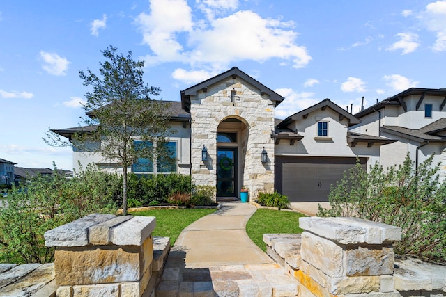 view of front facade featuring a garage, stone siding, driveway, and stucco siding