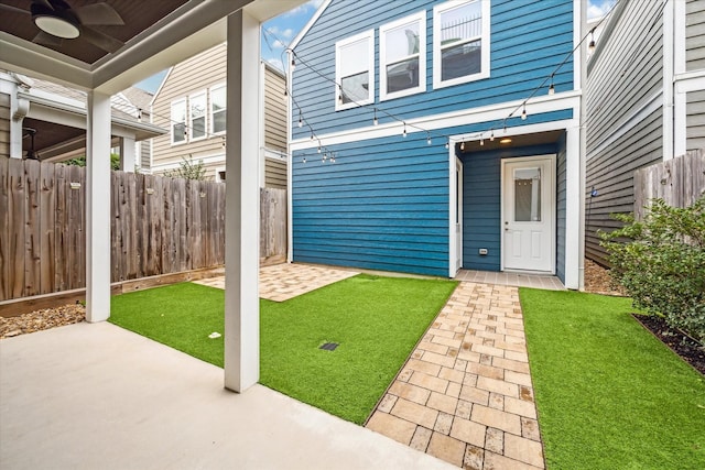 doorway to property featuring a lawn, a patio, fence, and ceiling fan