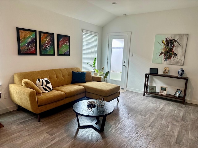 living area with baseboards, vaulted ceiling, and wood finished floors