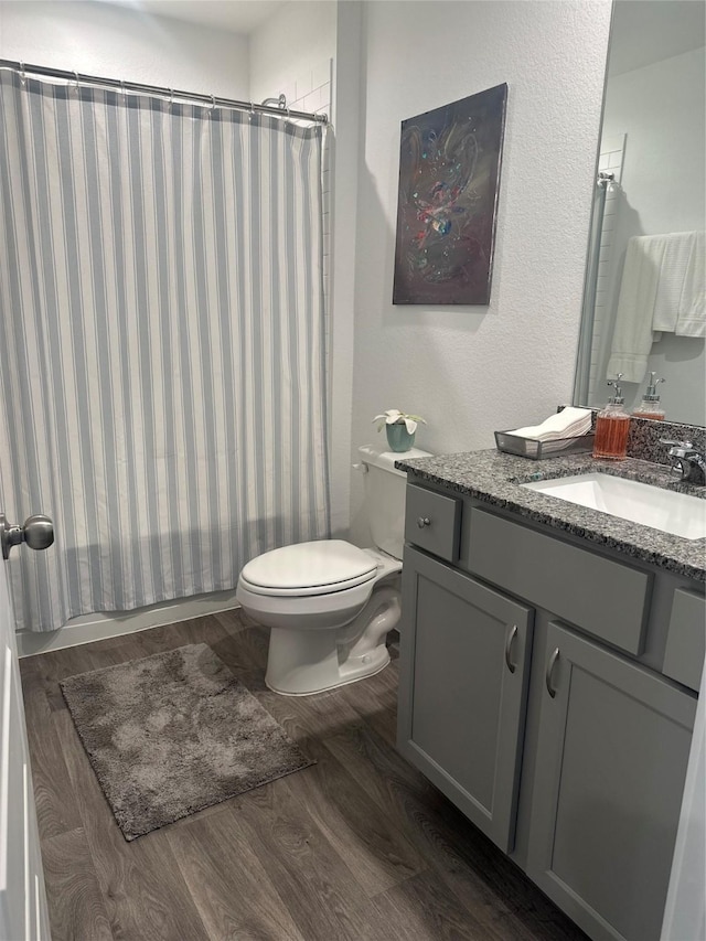 bathroom with toilet, shower / bath combo, wood finished floors, and vanity