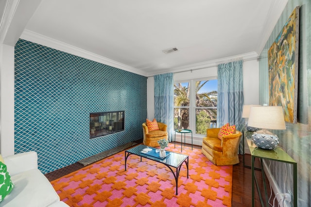 sitting room with crown molding, an accent wall, visible vents, and wallpapered walls