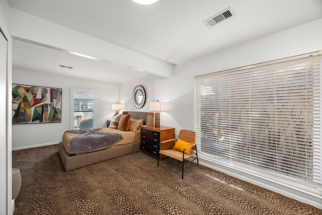 bedroom with visible vents, dark colored carpet, and beam ceiling