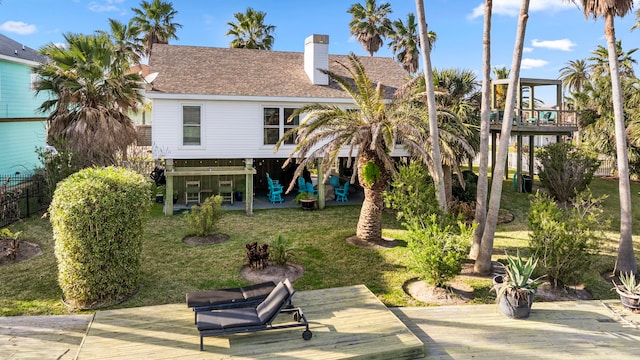 rear view of house featuring a patio, fence, a yard, roof with shingles, and a wooden deck