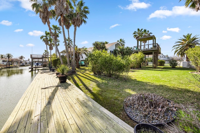 dock area with a water view, fence, and a lawn