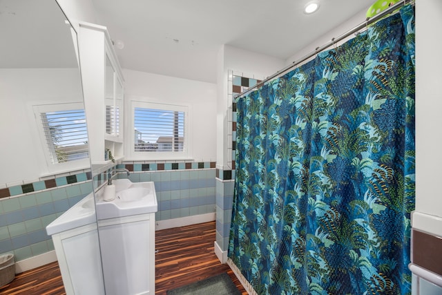 full bathroom with a wainscoted wall, wood finished floors, vanity, tile walls, and recessed lighting