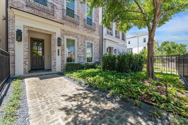 doorway to property featuring brick siding and fence