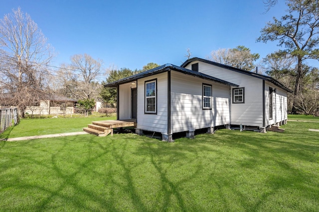 back of property featuring fence and a lawn