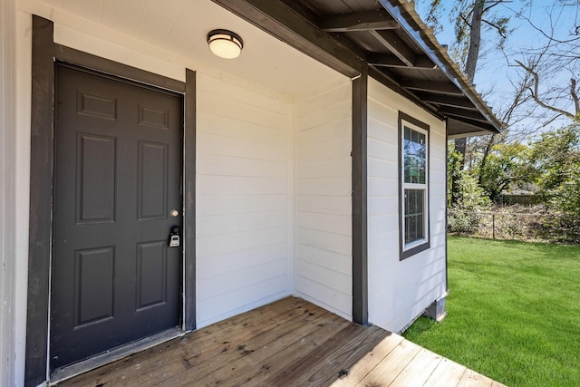 entrance to property featuring a yard, a deck, and fence