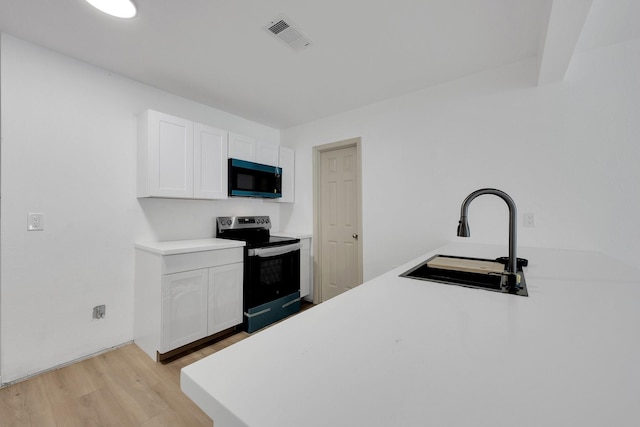 kitchen featuring light countertops, stainless steel electric range oven, a sink, and white cabinetry