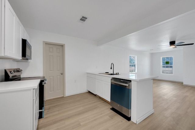 kitchen with a peninsula, white cabinetry, appliances with stainless steel finishes, and light countertops