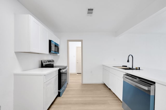 kitchen featuring a sink, stainless steel appliances, light countertops, and white cabinetry