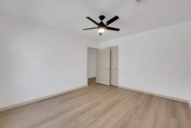 empty room featuring light wood finished floors, ceiling fan, visible vents, and baseboards