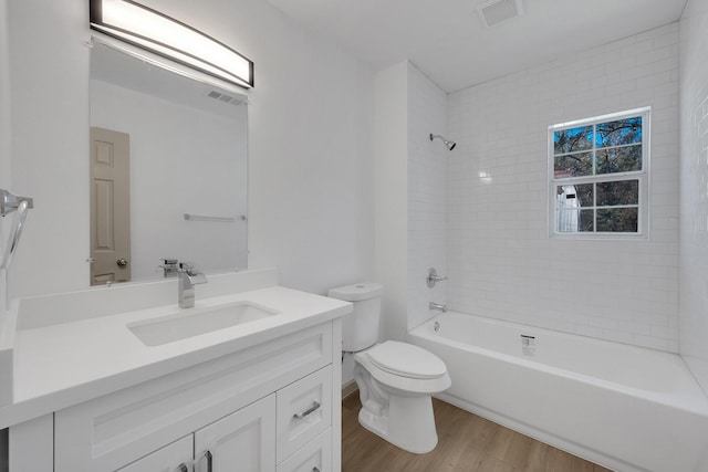 bathroom featuring toilet, wood finished floors, vanity, visible vents, and washtub / shower combination