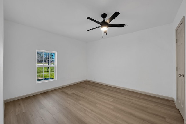 spare room with baseboards, a ceiling fan, and light wood-style floors