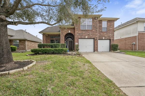 view of front facade featuring an attached garage, a front yard, concrete driveway, and brick siding