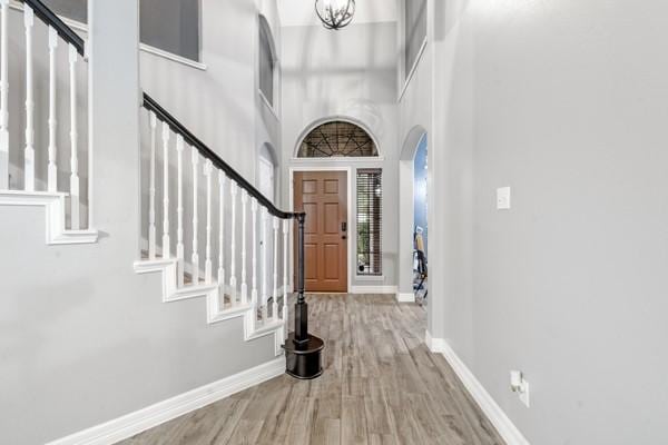 entrance foyer with a notable chandelier, light wood finished floors, baseboards, and stairs