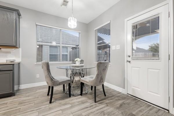 dining room with a notable chandelier, light wood-type flooring, visible vents, and baseboards