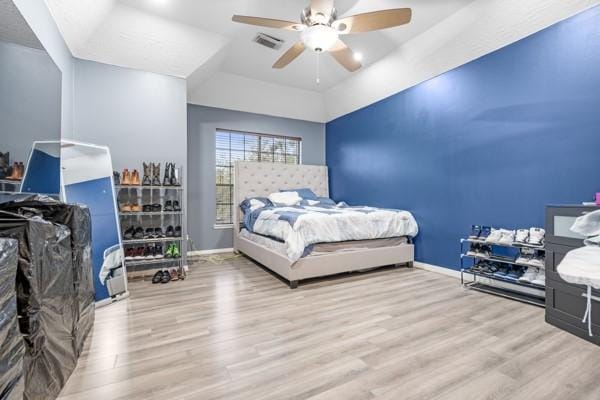 bedroom featuring light wood-type flooring, a raised ceiling, and baseboards