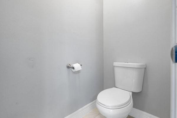 bathroom featuring tile patterned flooring, baseboards, and toilet