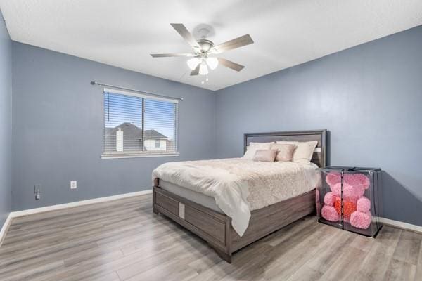 bedroom featuring a ceiling fan, light wood-style flooring, and baseboards