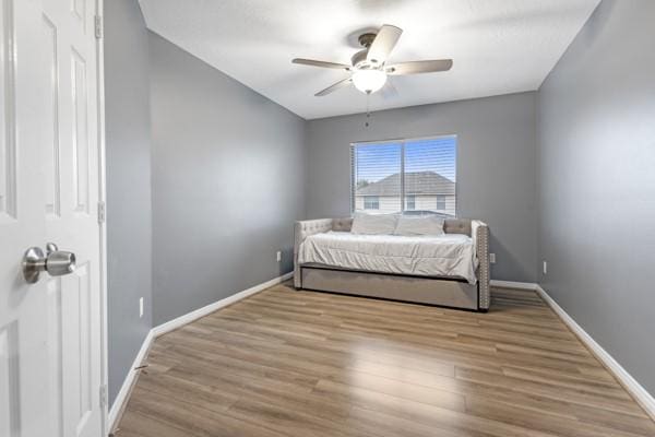 bedroom featuring ceiling fan, light wood finished floors, and baseboards