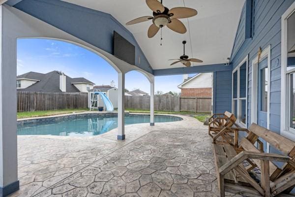 view of swimming pool featuring a fenced in pool, a patio, ceiling fan, a water slide, and a fenced backyard