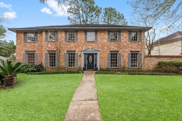 colonial home with a front yard and brick siding