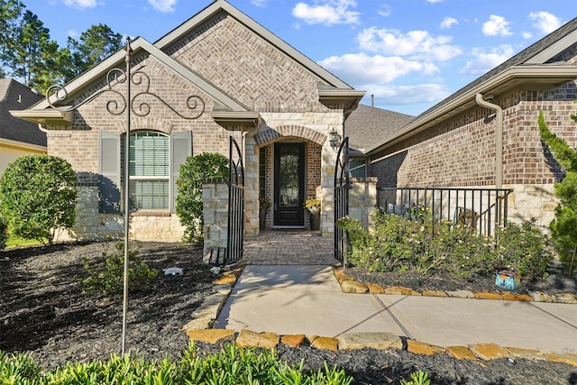 view of front of property featuring stone siding, brick siding, and fence