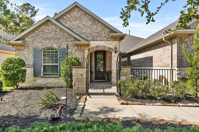 view of front facade featuring stone siding, a gate, brick siding, and fence