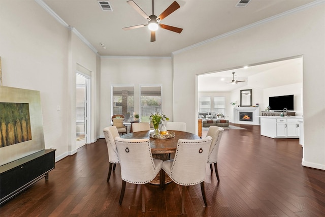 dining area with dark wood-type flooring, visible vents, baseboards, a ceiling fan, and a glass covered fireplace