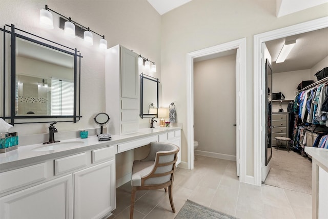 full bathroom featuring baseboards, toilet, tile patterned floors, a walk in closet, and vanity