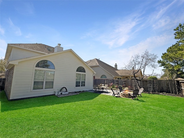 rear view of house featuring fence, a fire pit, a lawn, and a chimney