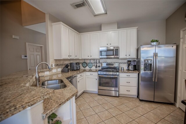 kitchen with a sink, stainless steel appliances, backsplash, and white cabinetry