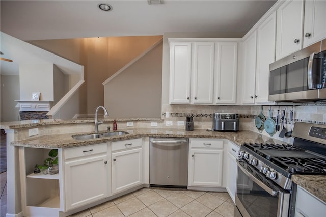 kitchen featuring decorative backsplash, a peninsula, appliances with stainless steel finishes, and a sink