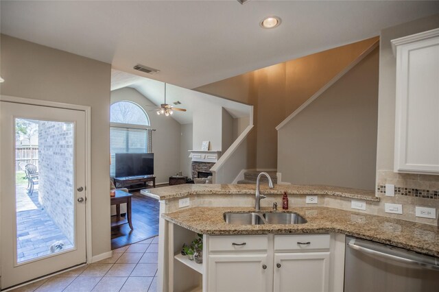 kitchen featuring a peninsula, light tile patterned flooring, ceiling fan, a sink, and dishwasher