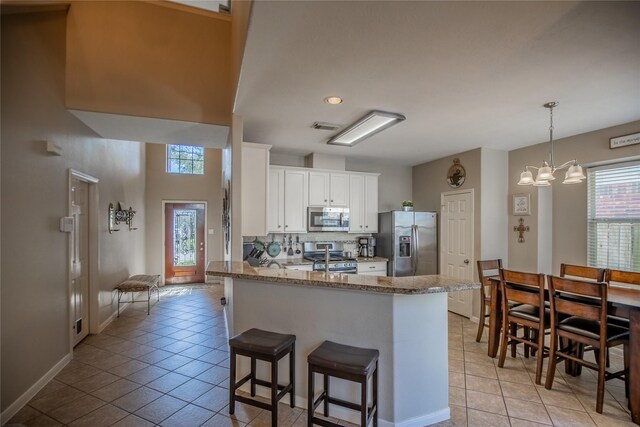 kitchen featuring visible vents, light stone counters, tasteful backsplash, appliances with stainless steel finishes, and white cabinets