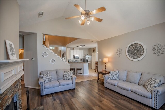 living room featuring visible vents, vaulted ceiling, a fireplace, wood finished floors, and a ceiling fan