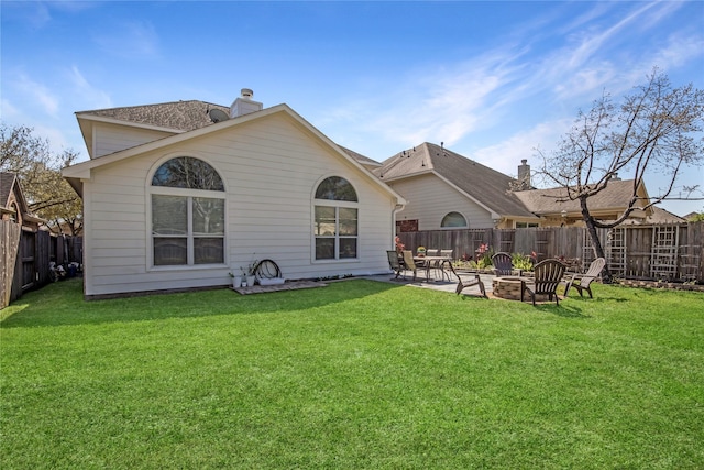 back of house with an outdoor fire pit, a lawn, a chimney, a fenced backyard, and a patio