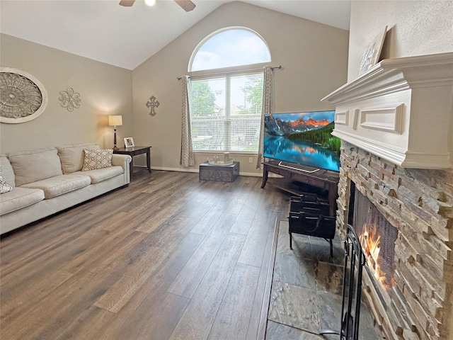 living room featuring a fireplace, a ceiling fan, baseboards, wood finished floors, and vaulted ceiling