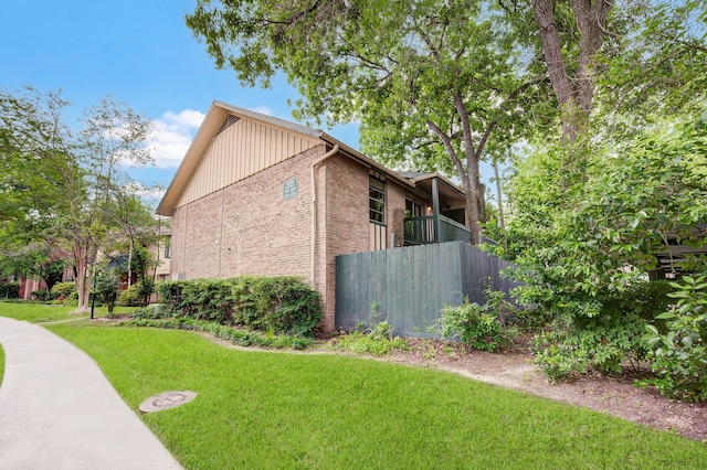 view of property exterior with brick siding, a lawn, and a balcony