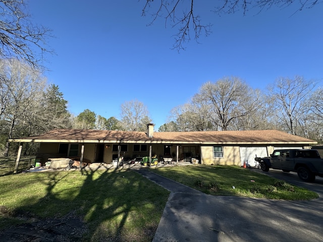 view of front of property with a garage, a front yard, and a chimney