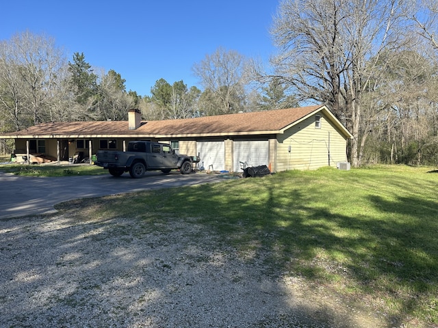 exterior space featuring a garage, a lawn, and a chimney