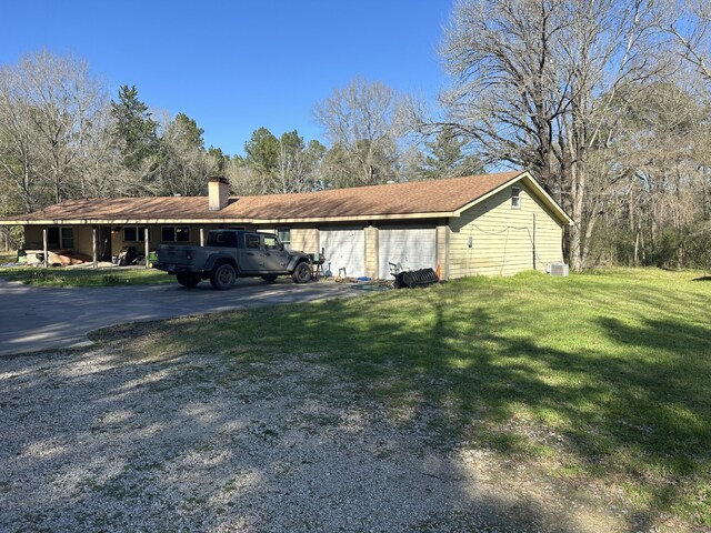 1030 Mangum Rd, Livingston, TX 77351 - view of side of home with a lawn, a garage, a chimney, and driveway