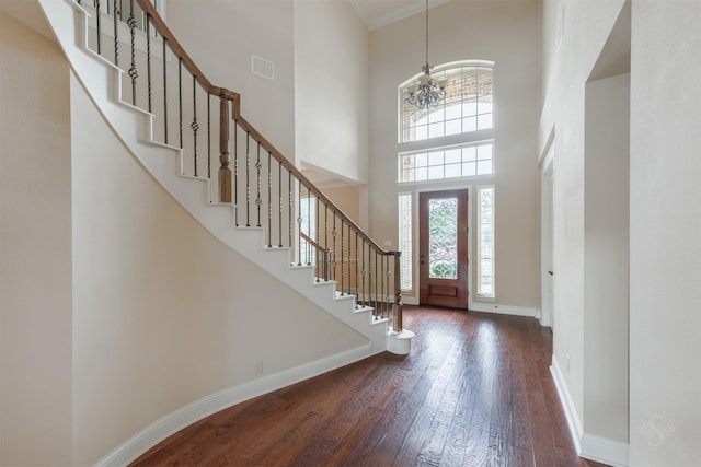 entryway featuring visible vents, a towering ceiling, dark wood-type flooring, a chandelier, and baseboards