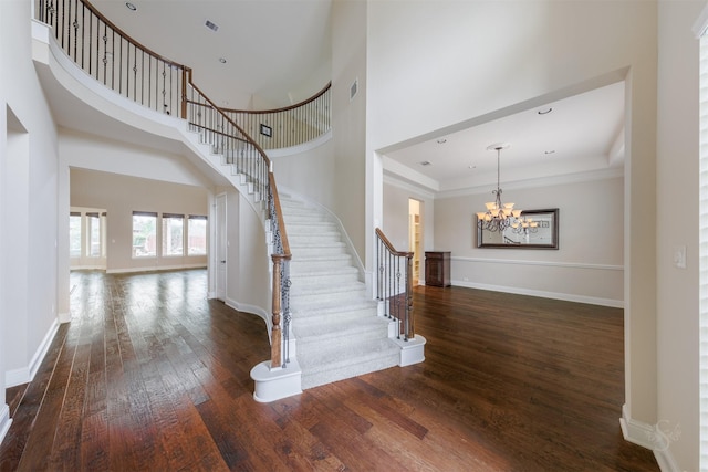 entrance foyer featuring an inviting chandelier, stairs, baseboards, and dark wood-type flooring